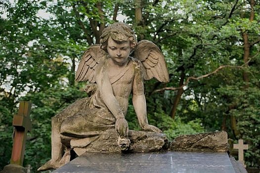 betonowa figura anioła siedzącego na płycie nagrobnej