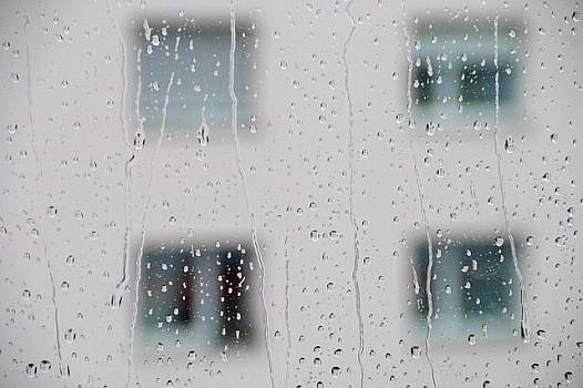 Widok bloku przez szybę w strugach deszczu