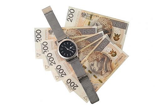 zegarek leżący na sześciu banknotach o wartości 200 zł