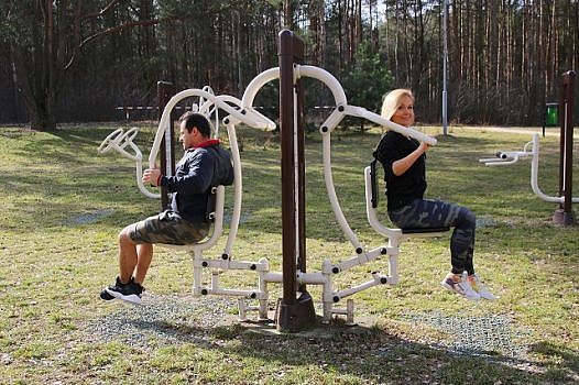 Trenerzy klubu fitness Fit Athletica - kobieta i mężczyzna na urządzeniu do ćwiczeń w parku na siłowni zewnętrznej