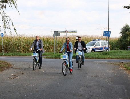 Trzy osoby jadące rowerem po drodze asfaltowej
