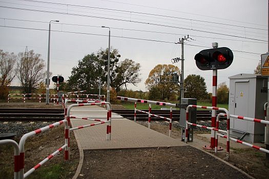 Przejście przez tory z rogatkami, sygnalizacją świetlną i barierkami.