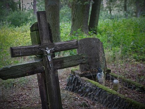 Zbliżenie na krzyże, w oddali stary nagrobek.