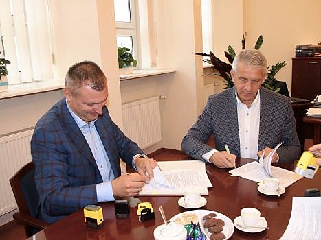 Na zdjęciu wójt gminy Suchy Las Grzegorz Wojtera i przedstawiciel wykonawcy inwestycji przy stole w urzedzie gminy podpisują umowę.