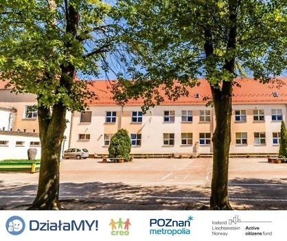 Widok Szkoły Podstawowej nr 1 w Suchym Lesie od tyłu. Na pierwszym planie drzewa. Na dole pasek z logotypami projektu.
