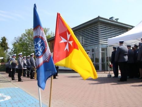 Flagi - policyjna i Gminy na tle Domu Osiedlowego w Biedrusku