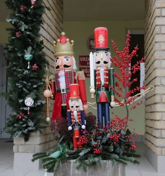 Zdjęcie przedstawiające drewnianych dziadków do orzechów w świątecznej scenerii przed urzędem gminy