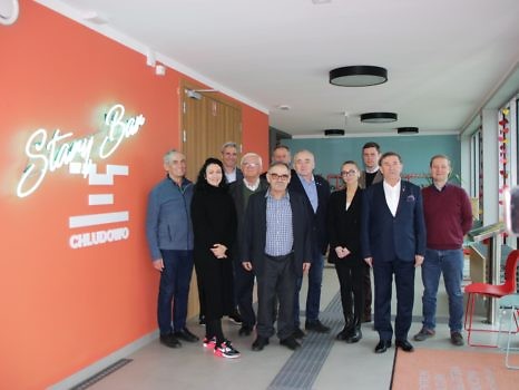 Uczestnicy spotkania na tle logo Starego Baru - neonu.