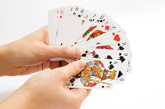 Na zdjęciu dłonie trzymające karty.