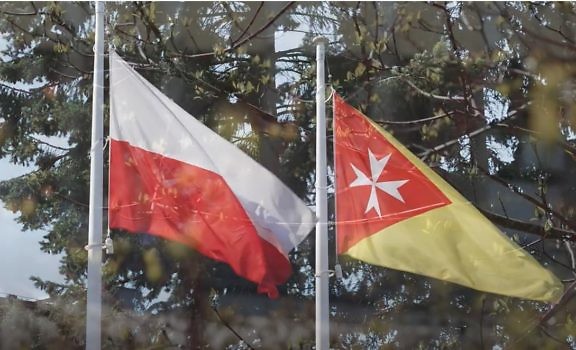 Dwie flagi - gminna i Polski, powiewające na masztach.