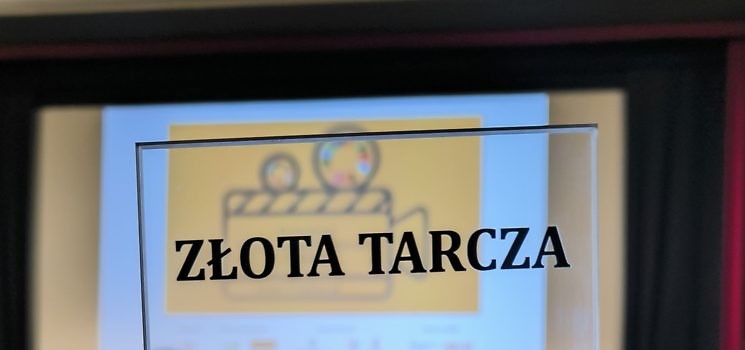 Zblizenie na statuetę Złota Tarcza, w tle slajd z logo IX Festiwalu Filmów Odpowiedzialnych
