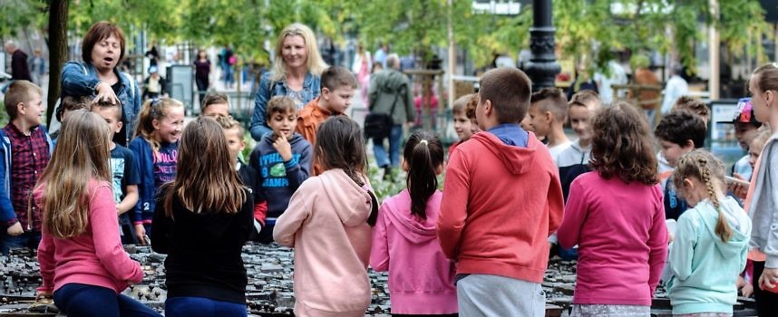 szkolna grupa dzieci, część dzieci stoi tyłem, część przodem