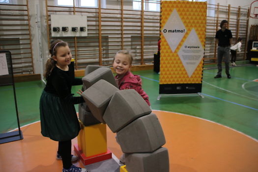 Dziewczynki układające most z klocków. 