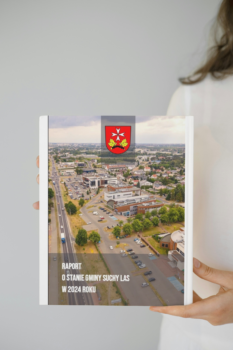 Fragment kobiety trzymającej okładkę, na której jest pierwsza strona raportu o stanie gminy.