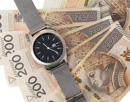 Banknoty, a na nich położony zegarek.