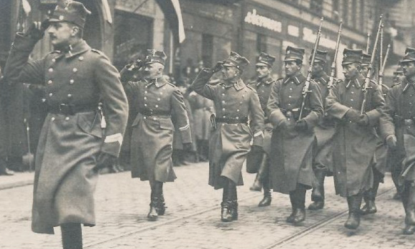 Żołnierze - powstańcy maszerujący ulicą. Zdjęcie archiwalne.