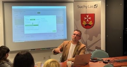 zbliżenie na szkoleniowca, w tle ekran i roll up z herbem Gminy Suchy Las