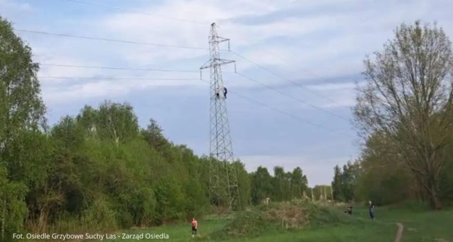 Zdjęcie przedstawiające linie wysokiego napięcia z wchodzącymi na słup chłopcami.