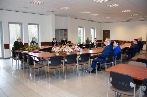 Widok na salę, w której przy owalnym stole siedzą jubilaci