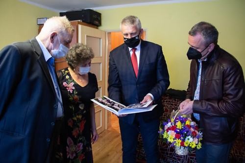 Wójt ogląda album ze zdjęciami Jubilatów, obok stoją Jubilaci i Radosław Banaszak 