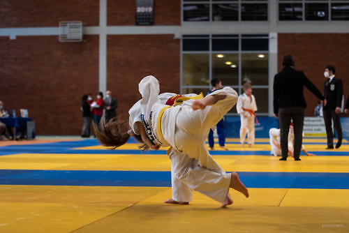 Zawodnicy judo podczas walki, moment rzutu na matę, w tle sędzia