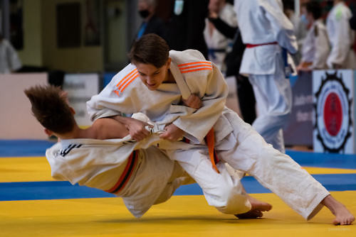 Dwóch zawodników judo walczy na macie.